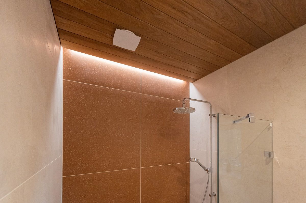 L'illuminazione d'accento sulla parete posteriore della doccia con strisce LED porta una bella luce in uno spazio nella scanalatura di un soffitto a pannelli che è stato lasciato scoperto.